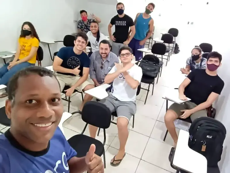 Professor de camisa azul do Foco faz selfie com a turma sentada nas carteiras