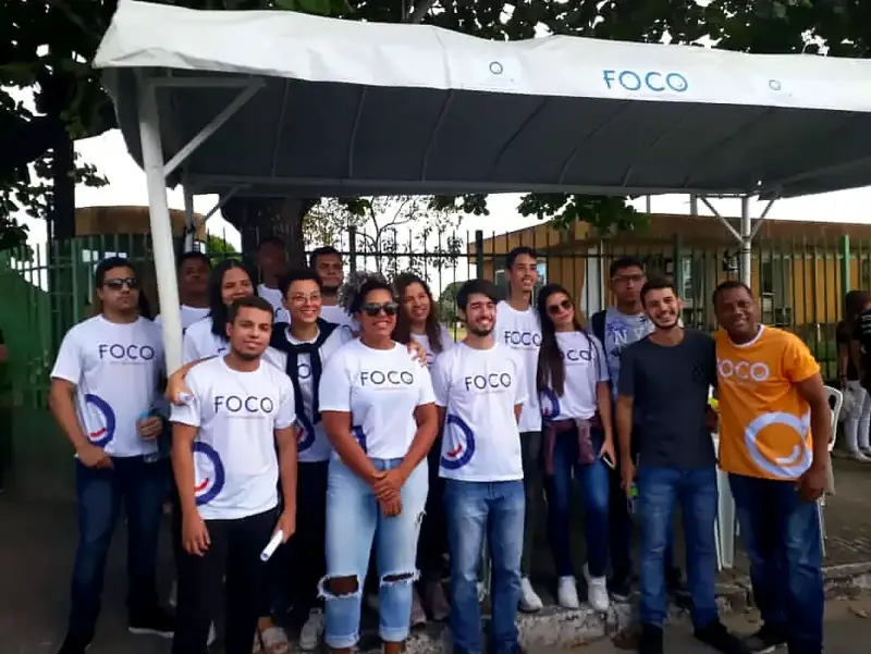 Alunos do Foco com a camisa do curso na frente da tenda branca do Foco, na rua